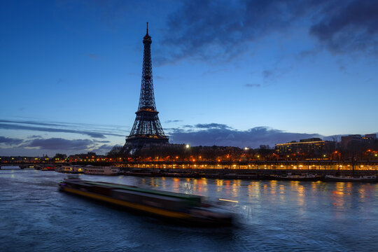 Eiffel Tower and Seine River at early morning first light with a passing barge. Port de Suffren in Paris, France