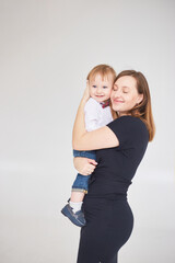 Mother holding her son. Woman and boy relax and playing on white background. Family, maternity, tenderness, parenthood, responsibility concept