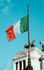 Vertical shot of an Italy flag with Vittoriano monument in Rome in the background