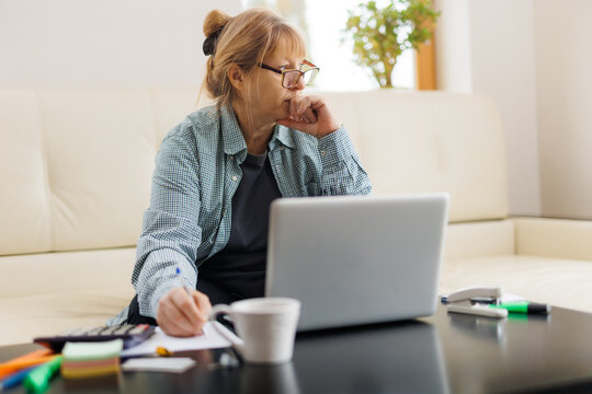 Active Mature Woman Using A Laptop For Remote Work From The Home Office. Video Conference, Video Meeting. Senior Teacher Leads Webinar