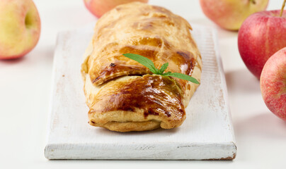 Baked strudel with apples on a white wooden board, delicious dessert