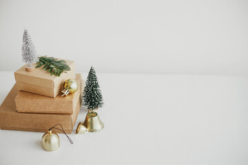 Stylish eco christmas gift boxes on white table. Simple craft christmas presents with golden baubles, tree and fir branch on rustic wood. Merry Christmas! Eco friendly holidays, space for text