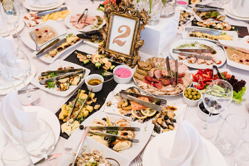 Festively laid table in a restaurant for an event. Cold appetizers and dishes on the wedding table. Top view. Close up.