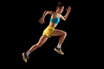 Young sportive woman, runner and jogger in motion action isolated on black background. Sport,...