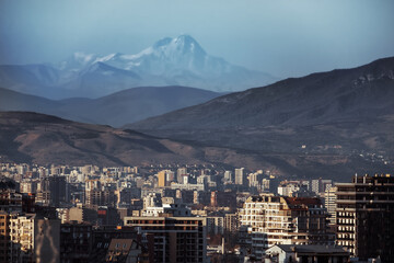 city of Tbilisi residential area of multi-storey buildings in rays of sunset against the backdrop of Mount Kazbek and  mountain landscape