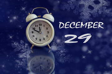 December 29 calendar: white alarm clock on a blue background with bokeh, reflection from objects, name of the month december, numbers 29