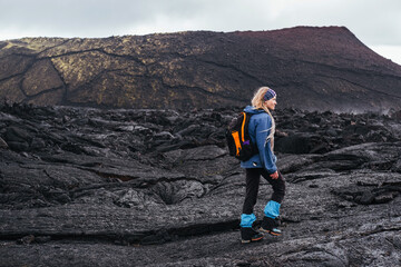 Woman tourist walking on frozen lava after Tolbachik volcanic eruption. Tourism in the land of...
