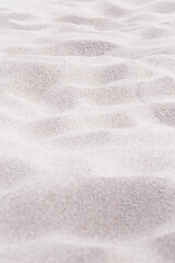 Fototapeta na wymiar Beige pink Sand texture natural background. Close up waves pattern on sand dunes, minimal nature vertical backdrop. Summer and travel, spa and relaxation concept. Selective focus.