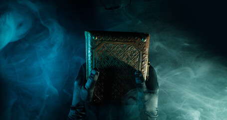 Mysterious antique book in the hands on a dark background. Horizontal banner with copy space for...