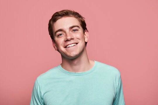 Glad young red hair man standing against pink background