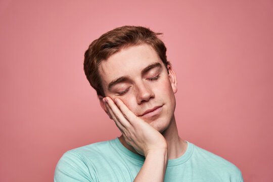 Young man touching cheek and sleeping