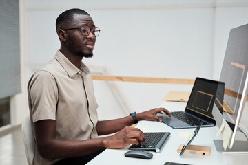 Portrait of programmer working on computer, testing code of new software