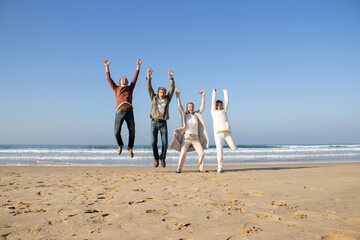 Excited senior friends having fun at beach on sunny autumn day. Four people laughing and jumping...