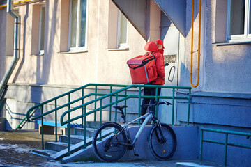 Doorstep food delivery. Man delivering pizza in thermo backpack to customers home, stand at the...