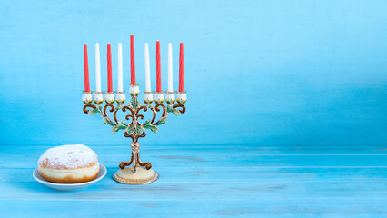 Menorah for Jewish holiday Hanukkah on blue wooden background with copy space.