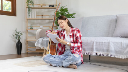 Asian woman specializes in music is composing the lyrics and melody for the opening of a new...