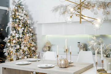 Christmas decor. Bright interior of white kitchen with decorated Christmas tree, garlands and Christmas wreaths.