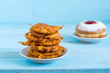 Batata latkes for Jewish holiday Hanukkah on blue wooden background. Traditional Hanukkah Batata Fritters.