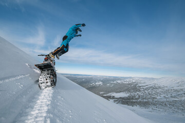 Snowbike rider jumping on steep snowy slope. Modify motorcycle with ski and special...