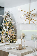 Christmas decor. Bright interior of white kitchen with decorated Christmas tree, garlands and Christmas wreaths.