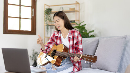 Woman artist playing the guitar and live or stream on laptop in the living room, Relaxation with music therapy, Provide enjoyment and entertainment to viewers or fan clubs, Music, Acoustic guitar.