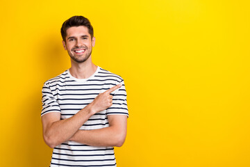 Photo of positive nice man beaming smile indicate finger empty space isolated on yellow color background