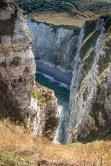 View on a secluded cove and sandy beach of Etretat between two cliffs and below these cliffs in Normandy, France