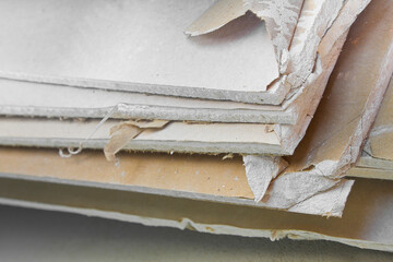 Demolished plasterboard wall, made of plaster and cardboard, with fragments of material and dust in...