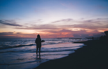 Lonely traveler standing on wet sandy beach