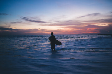 Unrecognizable person standing with surfboard in sea water near beach
