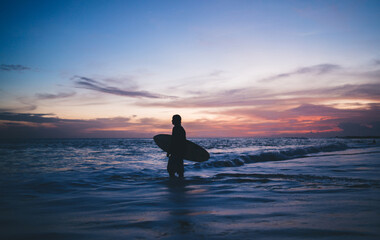 Anonymous man standing with surfboard in sea water
