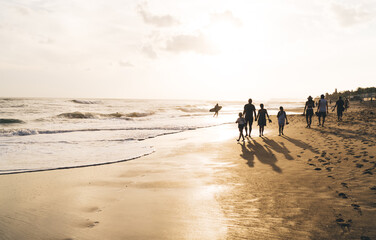 People walking on sandy beach with family members leisurely