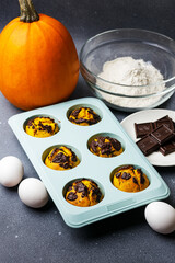 Pumpkin muffins baked in the silicone mold at the table with ingredients.