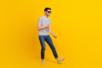 Fototapeta premium Full length photo of funky adorable man wear white t-shirt dark glasses having fun dancing isolated yellow color background
