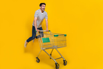 Full length photo of funky impressed man wear white t-shirt jumping high enjoying retail shopping isolated yellow color background