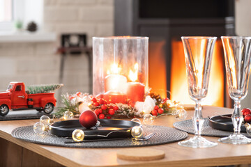 Festive interior of house is decorated for Christmas and New Year in loft style with black stove, fireplace, Christmas tree. Warm studio room with set table, burning wood, cozy and heating of home