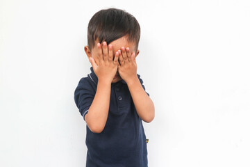 Cute little Asian boy shy, closing eyes with his fingers isolated on white background