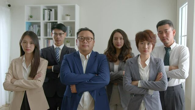 group of asian businesspeople with arms crossed in office..smiling young business professionals team standing among his colleagues.