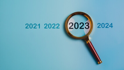 magnifier glass focus on the year 2023. Focus on new business goals, plan and strategy of the new...