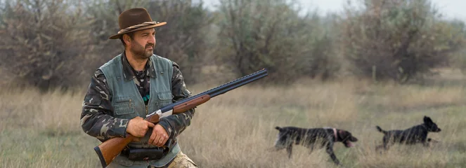 Gardinen Hunter man in camouflage with a gun during the hunt in search of wild birds or game. © Mountains Hunter