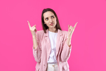 Happy young caucasian female in a pink jacket pointing fingers away