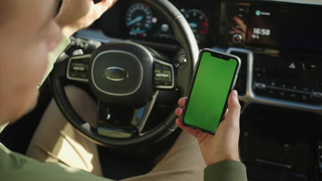 The driver has a handheld mobile phone with a green screen, chroma key. Car Interior Green Screen