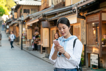 cheerful asian Japanese female visitor reading online travel info on cellphone on the traditional...