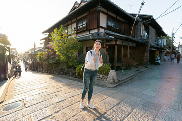 full length of lost asian Japanese female traveler standing at an intersection at Ninenzaka and Sannenzaka in Kyoto japan and looking into distance for right directions at dusk