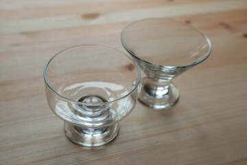 Empty ice cream glassware stands on the wooden surface of the table.