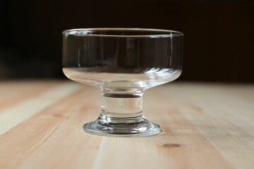 Empty ice cream glassware stands on the wooden surface of the table.