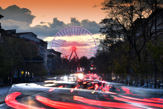 Christmas Holidays, illuminated Ferris wheel with traffic flowing along the avenues of the center of Florence. Italy. long exposure shot