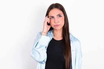 Fototapeta premium Young caucasian woman wearing blue overshirt over white background tries to memorize something, keeps fore finger on temple, reminds information for exam,
