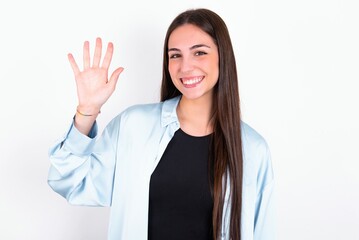 Young caucasian woman wearing blue overshirt over white background showing and pointing up with fingers number five while smiling confident and happy.