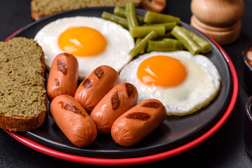Tasty English breakfast of fried eggs, beans, asparagus, sausages with spices and herbs